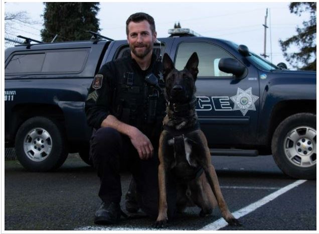 K9 Sgt. Rob Griesel kneeling beside Kuill with an EPD suv in the background