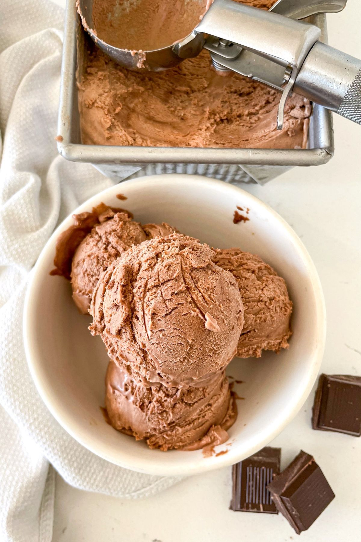 chocolate ice cream scoops in white bowl above