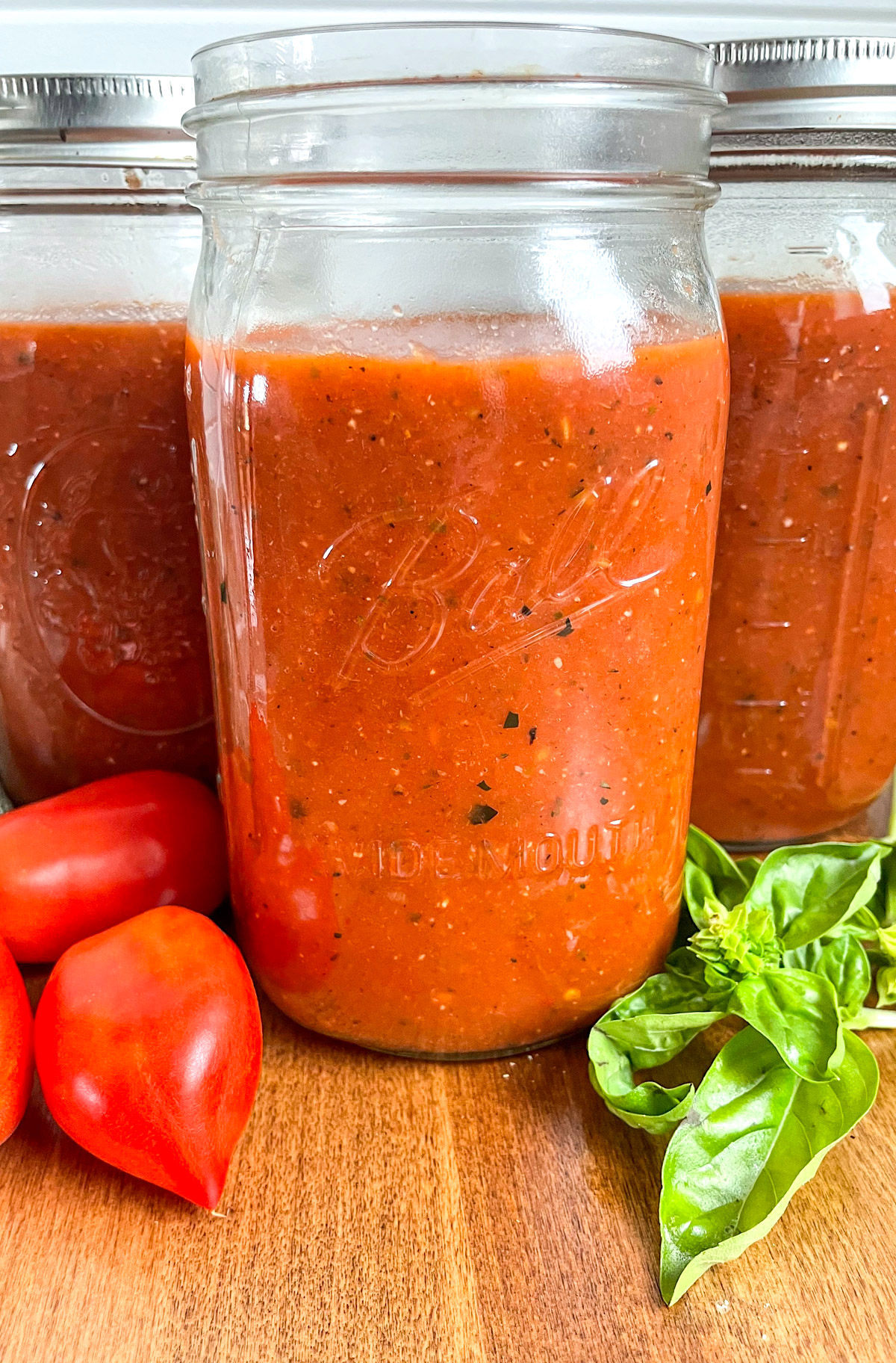 jars of roasted tomato sauce with fresh tomatoes and basil