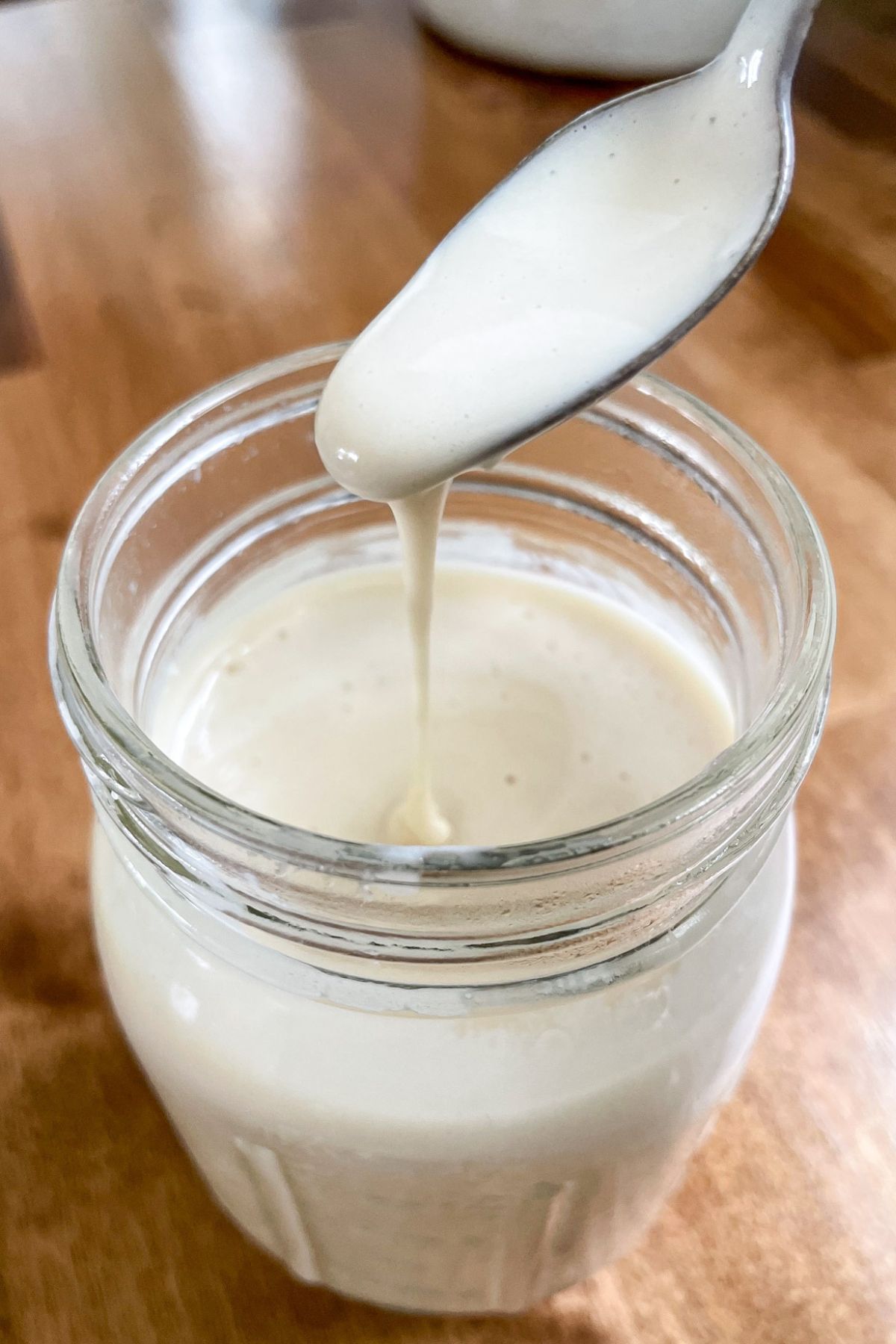 spoon of sweetened condensed milk pouring into jar