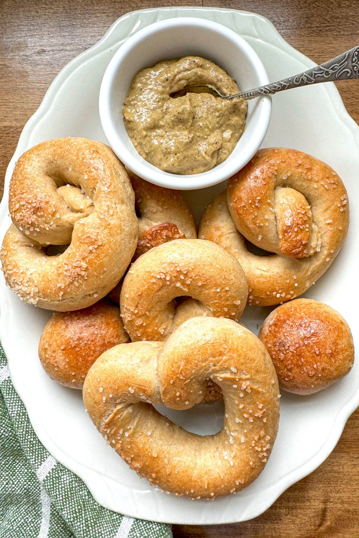 shaped, baked pretzels on a white platter with mustard