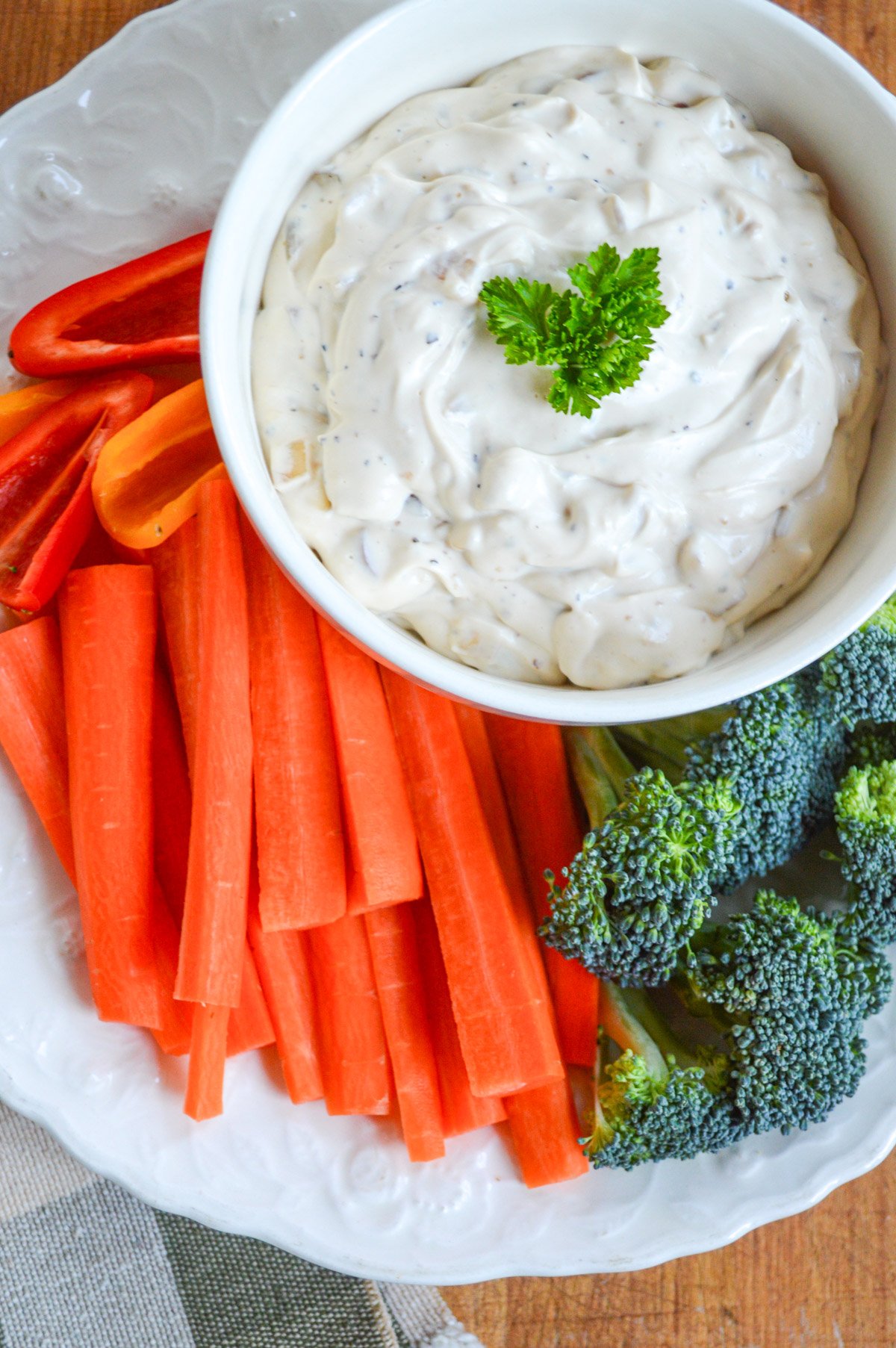 onion dip in white bowl with carrots and broccoli