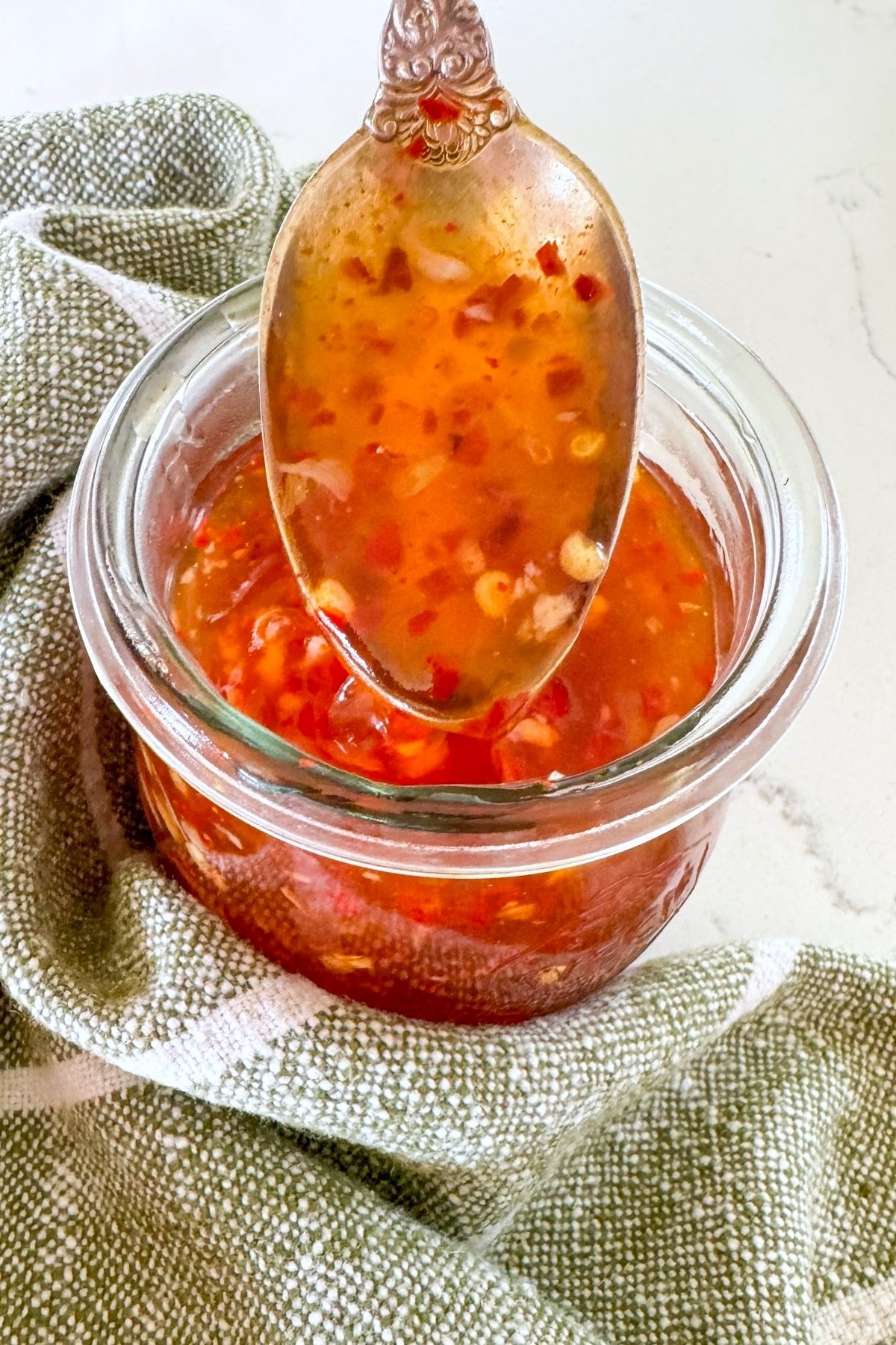 sweet chili sauce on a spoon over a jar