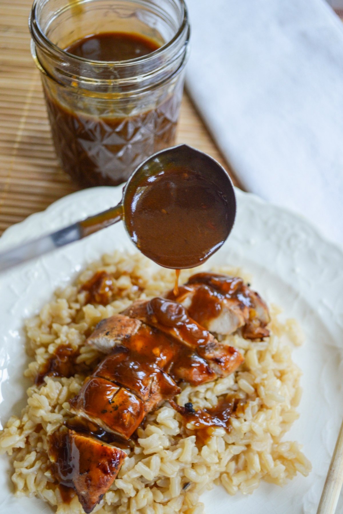 pouring teriyaki sauce on chicken and rice